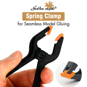 Golden Maple spring clamp for seamless model gluing, a model-making tool with orange gripping pads, held by hand.