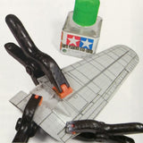 Spring clamps holding a model airplane wing securely during gluing, ideal for seamless assembly with Tamiya cement.