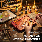 Using the painting palette tray and detail brush on a miniature model at a craft workbench.