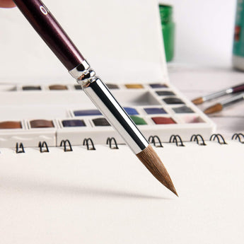 High-precision Kolinsky Sable watercolor brush with a fine point, used for detailed painting in a sketchbook.