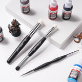 Miniature painting workspace with game color washes, goat hair drybrushes, and precision nylon detail tools.