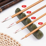 Traditional Chinese calligraphy brushes (G1, G2, G3, W1) with bamboo handles, displayed on a decorative jade brush rest.