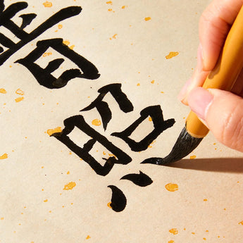 Uses a fine-tipped Watercolor Calligraphy Brush, writing black Chinese characters on textured, speckled paper.