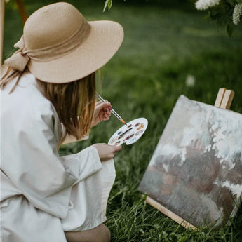 Professional Artist using a nylon travel brush, plastic palette with vibrant acrylic paint, creating art outdoors.